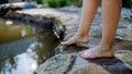 Unrecognizable young woman is dipping her foot in cool water of pond, refreshing and hardening concept. Royalty Free Stock Photo