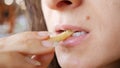 Unrecognizable young woman is eating french fries in fast food restaurant. She is holding one hand potato, mouth closeup