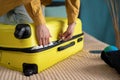 An unrecognizable young woman getting ready for the trip, vacation, travel, presses her foot on a crowded suitcase to Royalty Free Stock Photo