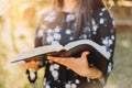 Unrecognizable young woman holding and reading her bible, outside with sun backlight. Spiritual revival Royalty Free Stock Photo