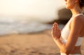 Unrecognizable young woman meditating alone on ocean beach, holding hands in namaste gesture, side view, copy space Royalty Free Stock Photo