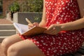 Unrecognizable Young woman in red dress Writing Gratitude Journal on wooden bench. Today I am grateful for. Self