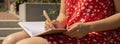 Unrecognizable Young woman in red dress Writing Gratitude Journal on wooden bench. Today I am grateful for. Self