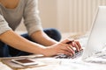 Unrecognizable young woman sitting on bed, working. Home office.