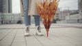 Unrecognizable young woman standing on city square with closed umbrella and spinning accessoire. Carefree Caucasian lady