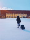 Unrecognizable young woman in a winter jacket walking towards Ivalo airport.