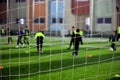 Unrecognized blurred young children players through the goal net exercising before a football game match on a soccer field, Royalty Free Stock Photo