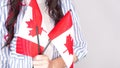 Unrecognized girl student in white blue shirt holding small canadian flag over gray background, Canada day, holiday, vote,