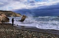 Unrecognized person looking and enjoying the stormy seascape of the Rock of Aphrodite at Paphos Cyprus