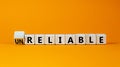 Unreliable or reliable symbol. Turned wooden cubes and changed the word unreliable to reliable. Beautiful orange background, copy Royalty Free Stock Photo