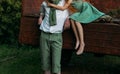 Unrequited first love. a barefooted girl in a green dress sits on the back of a car and hugs a barefoot, next to a standing guy, a Royalty Free Stock Photo