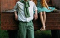 Unrequited first love. a barefooted girl in a green dress sits on the back of a car and hugs a barefoot, next to a standing guy, a Royalty Free Stock Photo