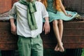 Unrequited first love. a barefooted girl in a green dress sits on the back of a car and hugs a barefoot, next to a standing guy, a Royalty Free Stock Photo