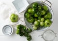 Unripe green tomatoes in colander and on table in white wooden kitchen background Royalty Free Stock Photo
