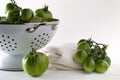 Unripe green tomatoes in colander and on table in white wooden kitchen background Royalty Free Stock Photo