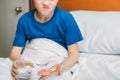 Unsatisfied boy holding glass of water and medicines in hospital bed Royalty Free Stock Photo