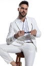 Unshaved fashion guy in white suit taking glasses off and posing Royalty Free Stock Photo