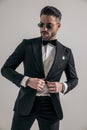 Unshaved young man looking away while buttoning black tuxedo Royalty Free Stock Photo