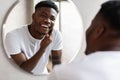 Unshaven African American Guy Touching Face With Bristle In Bathroom Royalty Free Stock Photo