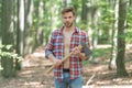 Unshaven axeman man in lumberjack style standing with axe forest background