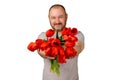 Unshaven happy middle-aged man holding a bouquet of red tulip flowers and an approving gesture with the other hand on a green Royalty Free Stock Photo