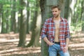 Unshaven lumbersexual man in unbuttoned lumberjack shirt forest background, copy space Royalty Free Stock Photo