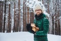 Unshaven smiling male holds pile of firewood, going to make fire to warm himself in frosty weather, spend winter day in forest, ha