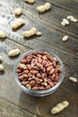 unshelled peanuts in a glass plate on a wooden background. peeled peanuts are scattered nearby. traditional beer snack Royalty Free Stock Photo