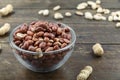 Unshelled peanuts in a glass plate on a wooden background. peeled peanuts are scattered nearby. traditional beer snack. Royalty Free Stock Photo