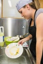 Unsmiling woman washing a plate