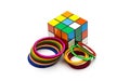 Dhaka, Bangladesh - 18 August 2021: Unsolved rubik puzzle cube with two piles of bobbin bangles on isolated white background