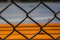 Unstoppable warm color, orange-red bench by the open-air cement basketball court inside the barbed wire Royalty Free Stock Photo