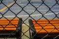 Unstoppable warm color, orange-red bench by the open-air cement basketball court inside the barbed wire Royalty Free Stock Photo