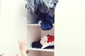 Untidy disoreder clothing closet. Messy home kid`s room. Young boy throwing dirty clothes in closet