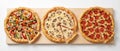 Three whole round pizzas with slices cut out, placed on a wooden board, top view. Royalty Free Stock Photo