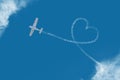 Flying plane among the clouds love heart sign