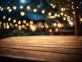 Empty wooden table top with decorative outdoor string lights in the garden at night time