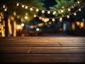 Empty wooden table top with decorative outdoor string lights in the garden at night time