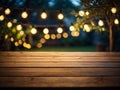 Empty wooden table top with decorative outdoor string lights in the garden at night time