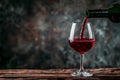 Poring red wine in a glass on the wood table with a gray background Royalty Free Stock Photo
