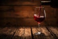 Pouring red wine in a glass on the wood table with a wood background Royalty Free Stock Photo