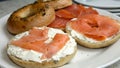 Two bagels sit on a white plate, one topped with slices of smoked salmon Royalty Free Stock Photo