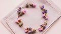 A wreath of small dried flowers, predominantly pink and purple, arranged in a circular pattern on a beige fabric background Royalty Free Stock Photo