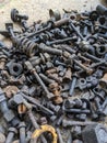 A collection of rusted bolts, nuts, and other metal fasteners is scattered on a concrete surface Royalty Free Stock Photo
