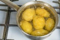 Untreated potatoes boil in a pot on a gas stove.