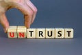 Untrust or trust symbol. Businessman turns wooden cubes, changes words `untrust` to `trust`. Beautiful grey table, grey backgr Royalty Free Stock Photo