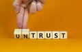 Untrust or trust symbol. Businessman turns wooden cubes, changes words `untrust` to `trust`. Beautiful orange table, orange Royalty Free Stock Photo