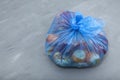 Unused fruits and vegetables. Rotten organic food waste in biodegradable plastic bag on gray background. Homemade composting