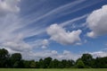 Unusual cloud formation in blue sky above trees and green field Royalty Free Stock Photo