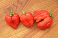 Unusual deformed mutant strawberry and heart shaped strawberry on wooden background
